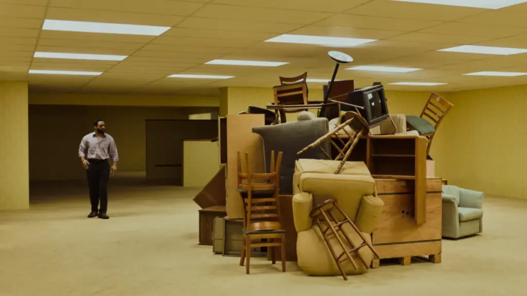 Chiwetel Ejiofor walks next to a large pile of chairs